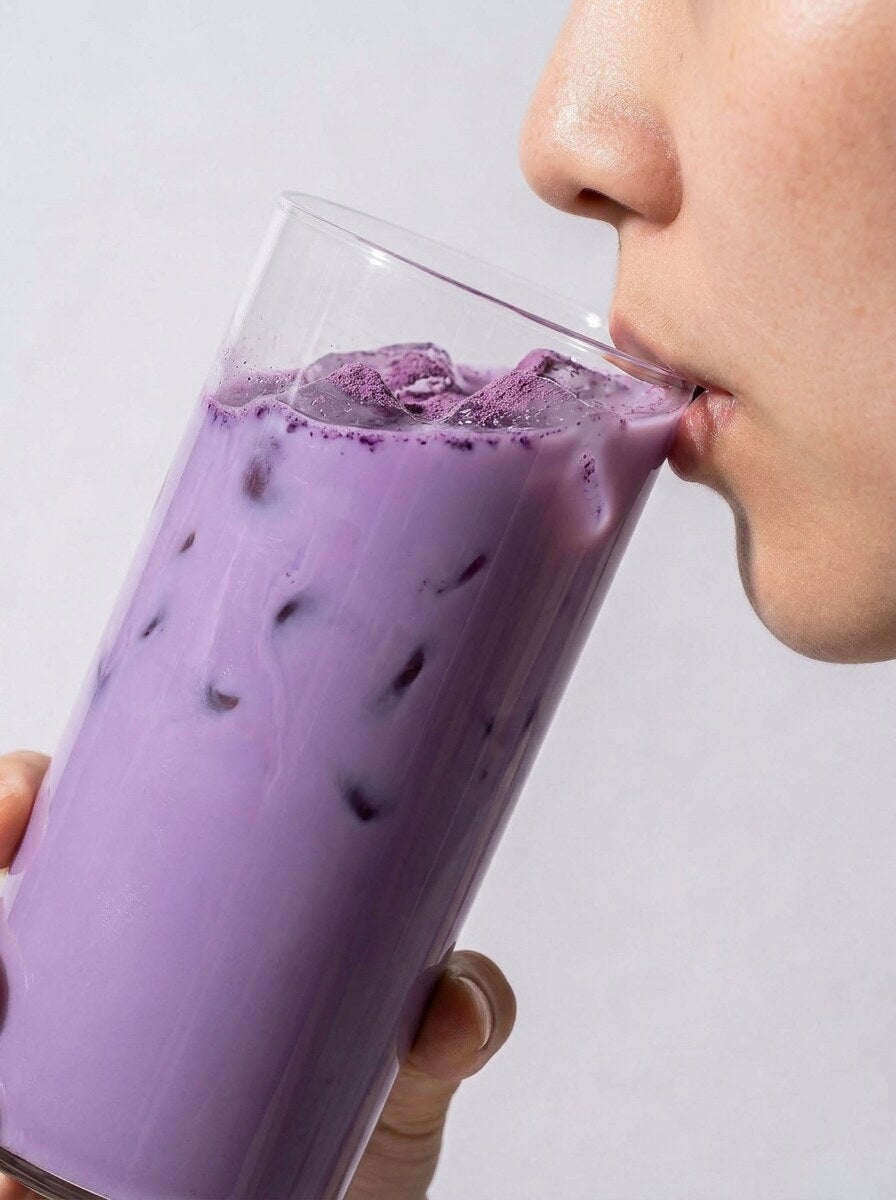 Woman serving an iced violet ube latte beside the UBurn pouch in a Parisian kitchen